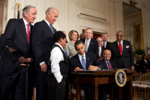 President Obama signs the ACA.